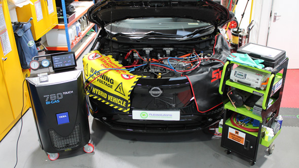 Image of a vehicle with its hood open, showcasing diagnostic equipment and tools, including a warning sign indicating 